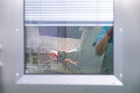 手术室 玻璃后面有一群外科医生蓝色药品团体装备诊所治疗防护房间职业情况图片