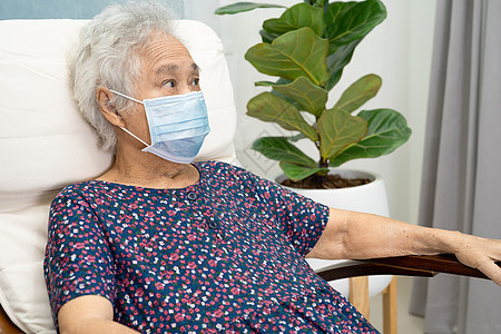 亚裔老年妇女在家房间里的摇椅上 坐着和轻松地享受着快乐女士退休女性医院祖母极乐骑术面具母亲椅子图片