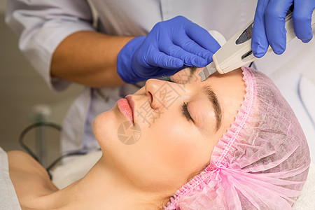 在化妆品美容院里 带着超声波设备 进行超声波剥皮的年轻caucasian女人医生身体治疗皮肤专家美容温泉内阁程序打扫图片
