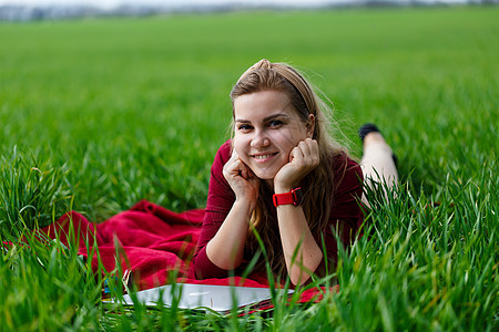 带着笔记本电脑的年轻漂亮女学生躺在草地上 在户外工作公园学生假期微笑互联网闲暇女孩成人快乐女士图片