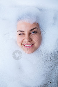 一个女孩在浴缸里的特写肖像和她脸上的白色泡沫 不同的情绪 鬼脸 女人的微笑肥皂卫生说谎成人淋浴女士女性皮肤气泡乐趣图片