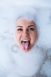 一个女孩在浴缸里的特写肖像和她脸上的白色泡沫 不同的情绪 鬼脸 女人的微笑皮肤浴室卫生女性护理洗澡乐趣说谎成人女孩图片
