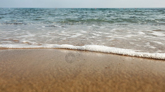 低角度/地平面照片显示海滩上湿沙 背景为海图片