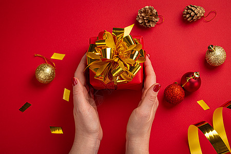 红金色握着红色和金色手的女子 圣诞节是顶端风景礼物女性丝带指甲油作品新年指甲盒子惊喜包装背景