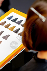 在美容院从发色图上选一个颜色的 年轻caucasians女人工作室女士目录造型服务头发美容师理发工作店铺图片