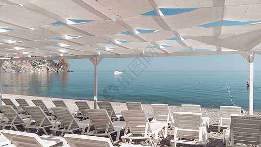 海滩上的天篷下空荡荡的躺椅 海滩区是空的 没有人 遮阳罩下的白色塑料日光浴床 假期结束 假期开始 等待游客蓝色天堂天空海岸线休息图片