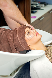美丽的年轻放松的女人 在美容院的一位专业理发师洗完澡后 把湿头发裹在毛巾上 笑声工作室造型师福利女士程序发型护理沙龙温泉女孩图片