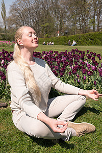 在公园的年轻美女 春郁金香在草坪上做瑜伽图片