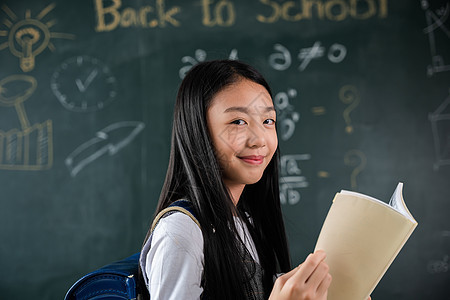 快乐的亚洲美丽的女学生站在教室黑板前拿着书本的课堂上女孩欢欣鼓舞黑色小学微笑幼儿园字母女性教育童年班级学习图片