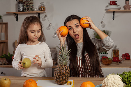 母亲和女儿正在做水果切菜 在厨房玩得开心些女士营养菜单菠萝食物用具孩子成人青菜橙子图片