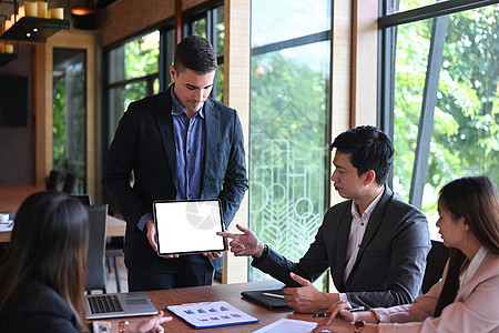 自信的商务人士拿着数字平板电脑 在会议室向商业伙伴展示新项目图片