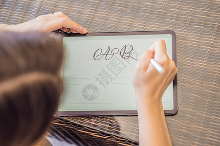 书法家年轻女子在数字平板电脑上写下短语 题写装饰字母 书法 平面设计 刻字 手写 创作女性绘画插图工作女孩字体教育草图触摸屏邮政图片