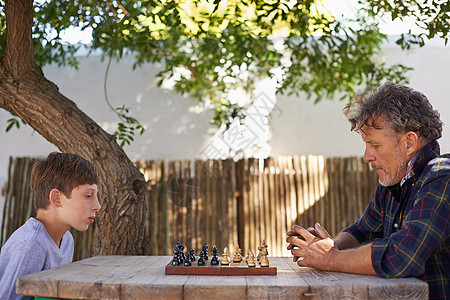 与他的祖父磨练他的国际象棋技巧 一个小男孩和他的祖父下棋图片