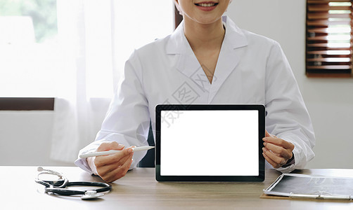 有经验的医生女性心脏病学家的肖像展示了现代技术白屏板 她使用的是检查室咨询病人穿白色大衣制服的听诊器耳目镜保健药剂师中心卫生外套图片