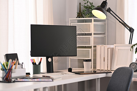 现代家庭办公室内部白色桌上的空白计算机屏幕 文具和灯台;在图片