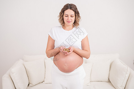 孕妇拿着一小撮核桃小吃脂肪怀孕卫生腹部坚果妈妈肚子婴儿早餐图片