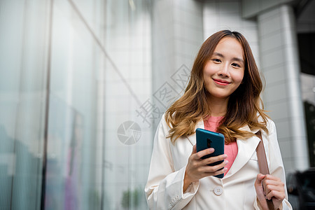 亚洲商业女发短信的智能手机打字工作技术人士商业商务女士城市办公室代理人街道金融图片