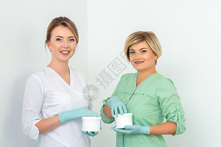 两家化妆品师配有蜡罐 用来在白色背景下微笑沉没 天然产品用于摘发 复制空间女孩蜂蜜女士头发脱毛洗剂广告润肤皮肤手套图片