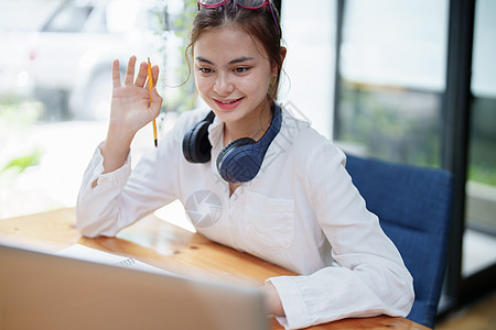 在视频会议期间使用电脑和耳机的女性电话微笑摄影教育讨论企业家团队学习办公室笔记本图片