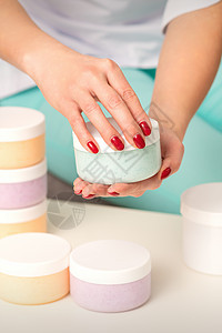 女性用手在桌子上开一个白体奶油罐 并配有许多瓶化妆品指甲治疗洗剂美甲护理手指女士保健呵护润肤图片