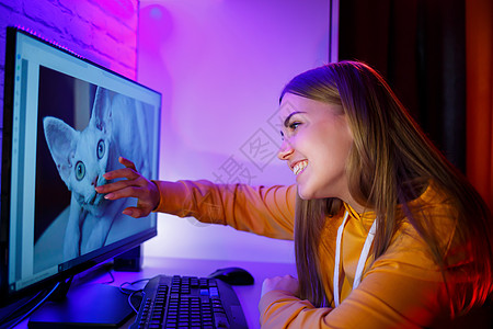 女孩自由职业者看猫的电脑屏幕 坐在一个计算机服务台的公寓里E咖啡猫咪笔记本女性头发胡须工作学校商业技术图片