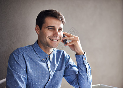 每个客户都对他很重要 一个自信的年轻商务人士 坐在办公桌旁在电话里聊天 他需要你帮忙吗?图片