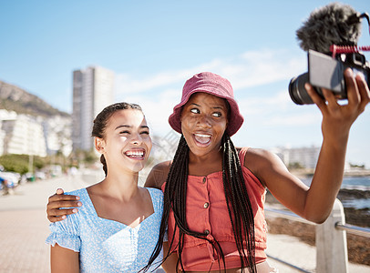 在城市 夏季和蓝天的社交媒体上 有影响力的女性朋友在海滩直播海滩度假或度假 z 世代女孩夫妇或自拍肖像中的人或靠近海洋的户外播客图片