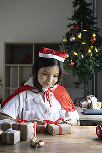 微笑的年轻女子在家包着圣诞礼物图片