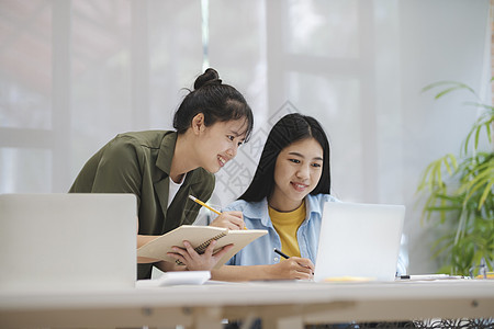 年青的亚洲大学生在学习上讨论计算机工作的问题 他们正在学习训练技术班级友谊课堂同事教学团体教科书阅读图片