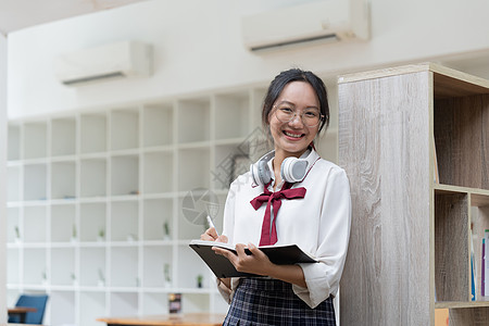 年轻女学生在图书馆工作 亚裔妇女在教科书中作笔记 男女学校成人学习商业微笑视频女孩技术笔记本桌子图片