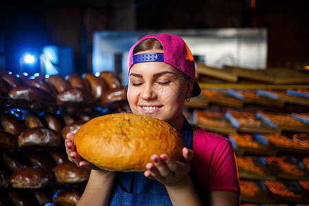 在面包店烘烤的阶段 在面包店货架的背景下 一个手里拿着面包的面包师女孩的画像 面包师的手用面包 工业面包生产商业自动化厨房面粉青图片