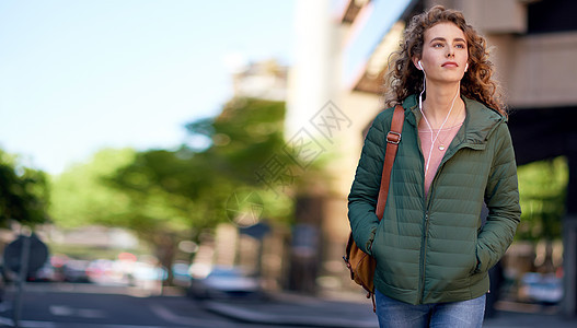 走在城市街道上的美女戴着耳机听音乐城市生活方式街道微笑音乐旅行幸福通勤者人行道技术女士红色图片