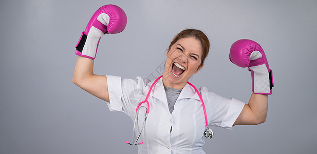 一名女医生用粉色拳击手套举起她的手 作为战胜这一疾病的标志胜利治疗癌症幸存者活动死亡药品活力捐款保健图片