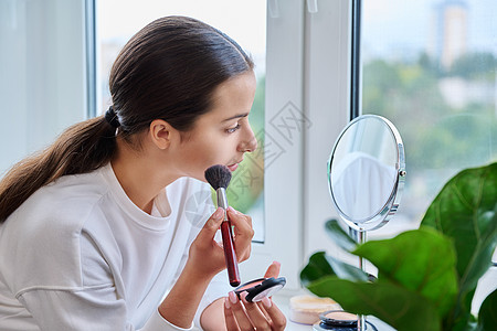 有镜子的年轻女性 每天早上化妆 在窗台上家里做日间化妆艺术家粉末青年女孩皮肤反射青少年头发女士刷子图片