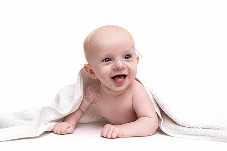 一个快乐的新生儿 笑在白色背景上 从毛巾下偷看出来图片