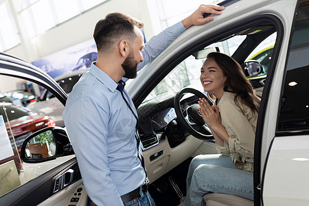 一位年轻妇女乞求丈夫在汽车经销店购买一辆新车图片
