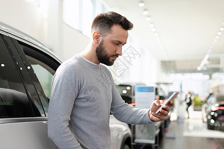 汽车经销中心的买方选择了一辆汽车 通过互联网将智能手机的价格与价格作比较图片