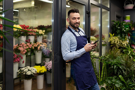 拥有丰富经验的男花店员 在冰箱背景上用新鲜鲜花束图片