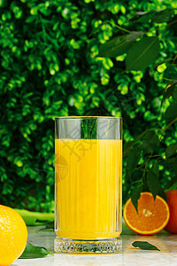 一杯新鲜橙汁 绿色背景上含新鲜果实的鲜橙汁树叶玻璃热带果汁食物液体水果桌子饮食乡村图片