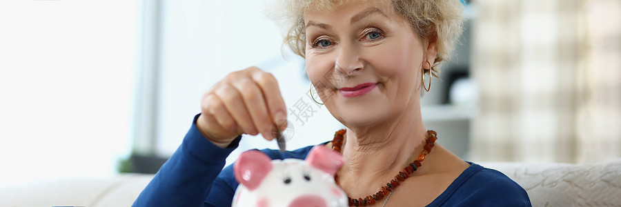 年长妇女把硬币放进小猪银行图片