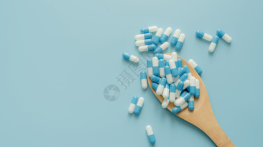 在木匙子和蓝色背景的青白色抗生素胶囊药片 抗生素耐药性 处方类药物 医疗 医药保健 抗菌药物 世界药剂师日图片