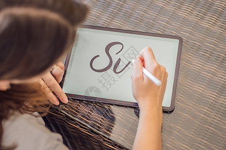 书法家年轻女子在数字平板电脑上写下短语 题写装饰字母 书法 平面设计 刻字 手写 创作设计师插图网络铅笔互联网打印作坊触摸屏人手图片
