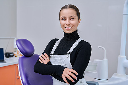 年轻笑笑的少女坐在牙科椅上看着镜头的肖像病人访问幸福保健矫正办公室医生牙齿女孩卫生图片