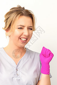穿着粉红色手套的caucasian女医生快乐地庆祝白种背景并举起拳头工人粉色女孩喜悦万岁惊呼成就情绪女士胜利图片