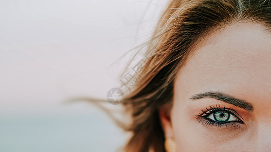 近距离接近绿眼女性 化妆美容的女性 半张脸和头发在风中吹起的发型背景图片