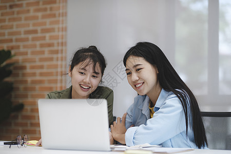 年轻亚裔女学生与朋友一起阅读书籍 为考试做准备 (续)图片