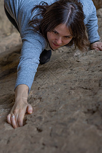 户外攀岩青年女子攀岩登山者挑战力量训练悬崖女性肾上腺素风景登山成功背景