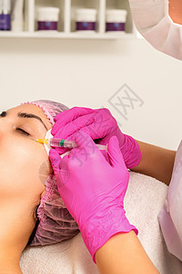 年轻白人女子在美容院里 接受青春的面部注射 眼睛上涂着血压酸身体手术美容师医生皮肤沙龙注射器护理女士药品图片