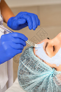 有刷子的美容师在美容诊所对女性病人面部使用光化学和液晶皮剥皮面具来遮住脸部程序治愈者皮肤奶油护理美丽沙龙化妆品杏仁女士图片