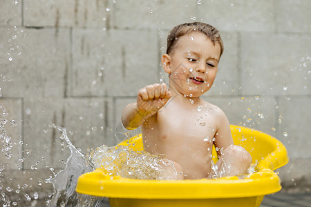 可爱的小男孩在户外的黄色浴缸里洗澡 快乐的孩子在泼水 玩水 玩得很开心 夏季和娱乐 在炎热的夏季保持凉爽 在后院玩水婴儿假期青年图片